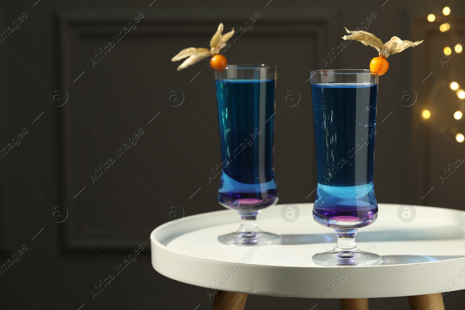 Photo of Refreshing cocktails decorated with physalis fruits on white table indoors. Space for text