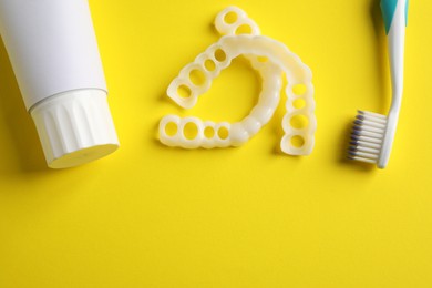 Photo of Bite correction. Toothpaste, brush and dental mouth guards on yellow background, flat lay. Space for text