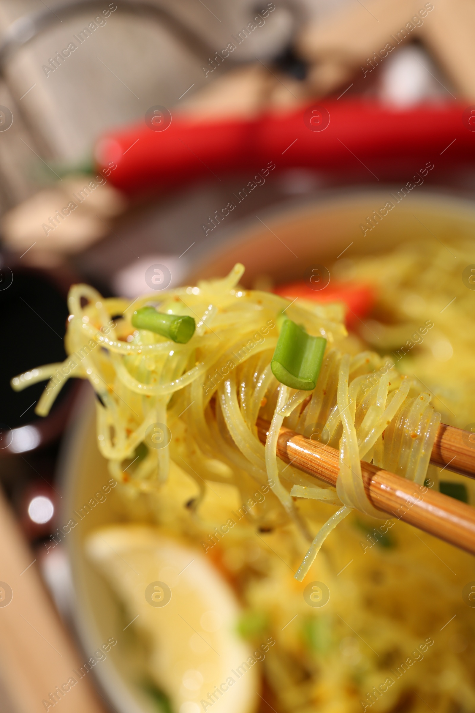 Photo of Stir-fry. Eating tasty noodles with chopsticks at table, closeup