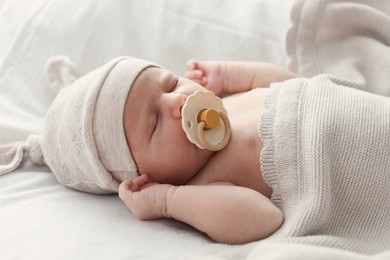Photo of Adorable little baby with pacifier sleeping in bed