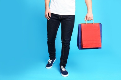 Photo of Young man with paper bags on blue background, closeup