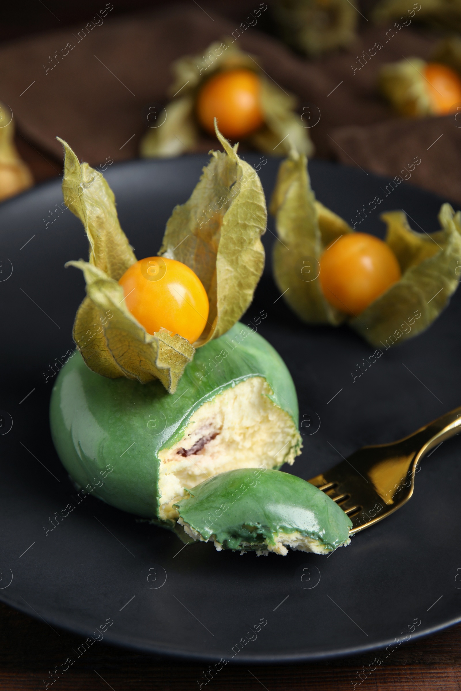 Photo of Delicious mousse cake decorated with physalis fruit on plate, closeup