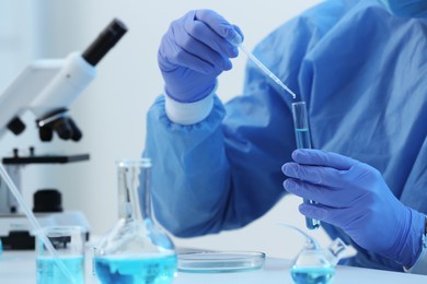 Photo of Scientist dripping sample into test tube in laboratory, closeup. Medical research