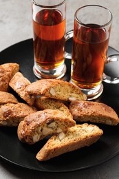 Photo of Tasty cantucci and glasses of liqueur on grey table, closeup. Traditional Italian almond biscuits