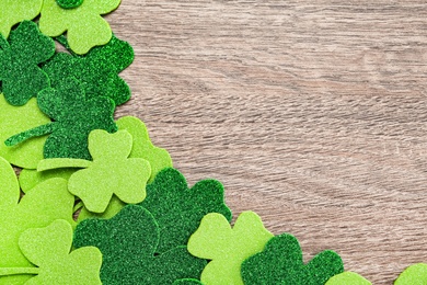 Photo of Decorative clover leaves on grey wooden table, flat lay with space for text. Saint Patrick's Day celebration