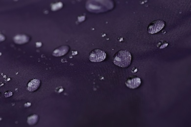 Photo of Purple waterproof fabric with water drops as background, closeup