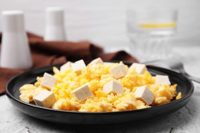 Plate with delicious scrambled eggs and tofu on white textured table