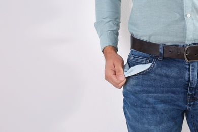 Photo of Man showing empty pocket on light background, closeup. Space for text