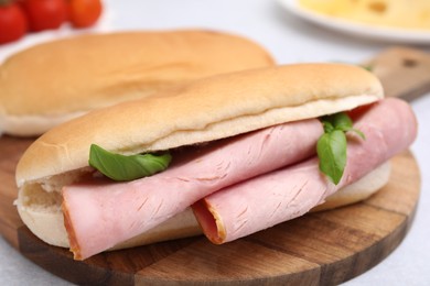 Photo of Delicious sandwich with ham and basil on table, closeup