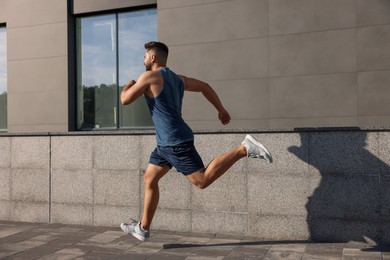 Healthy lifestyle. Young man running near building outdoors