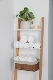 Photo of Soft towels on decorative ladder near white wall