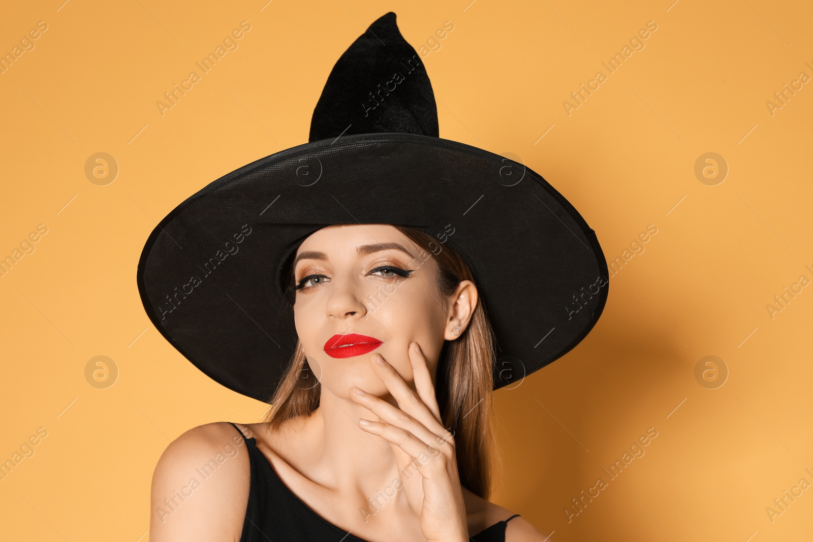 Photo of Beautiful woman wearing witch costume for Halloween party on yellow background