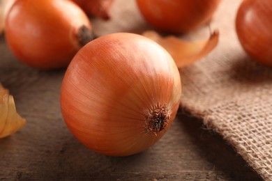 Many ripe onions on wooden table, closeup