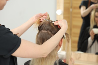 Hair styling. Professional hairdresser working with client in salon, closeup