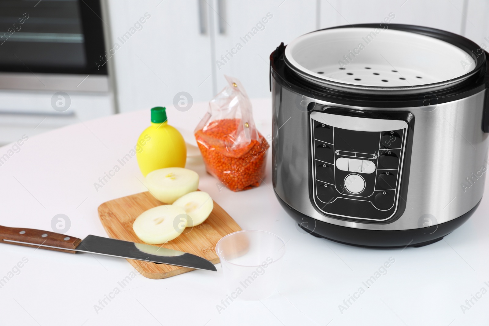 Photo of New modern multi cooker and products on table in kitchen