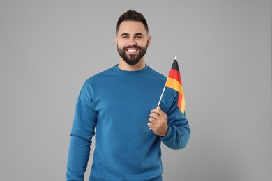 Photo of Young man holding flag of Germany on light grey background