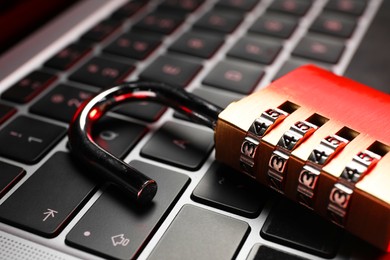 Photo of Cyber security. Metal combination padlock on laptop, closeup