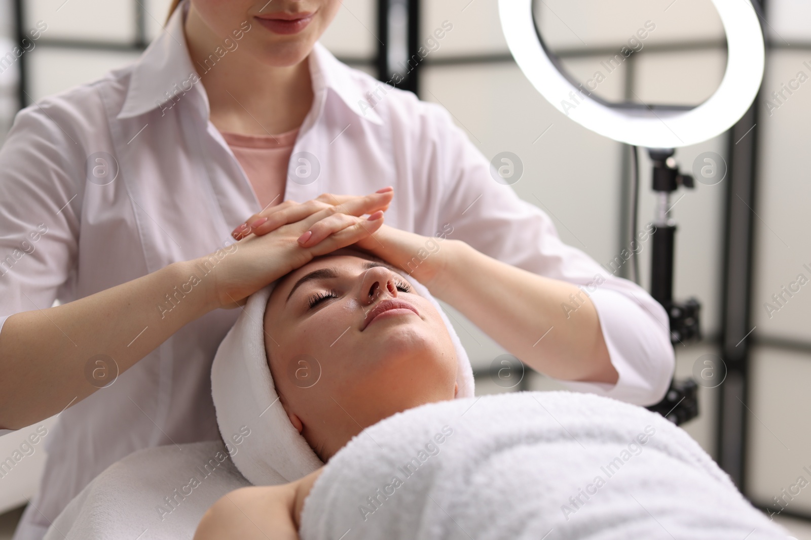 Photo of Cosmetologist making face massage to client in clinic, closeup