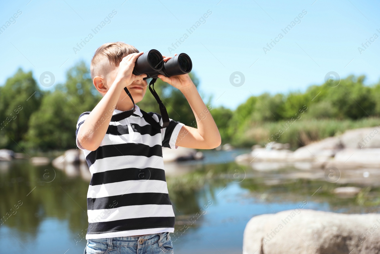 Photo of Little boy with binoculars outdoors. Summer camp