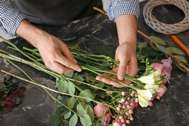 Photo of Male florist creating beautiful bouquet at table, closeup