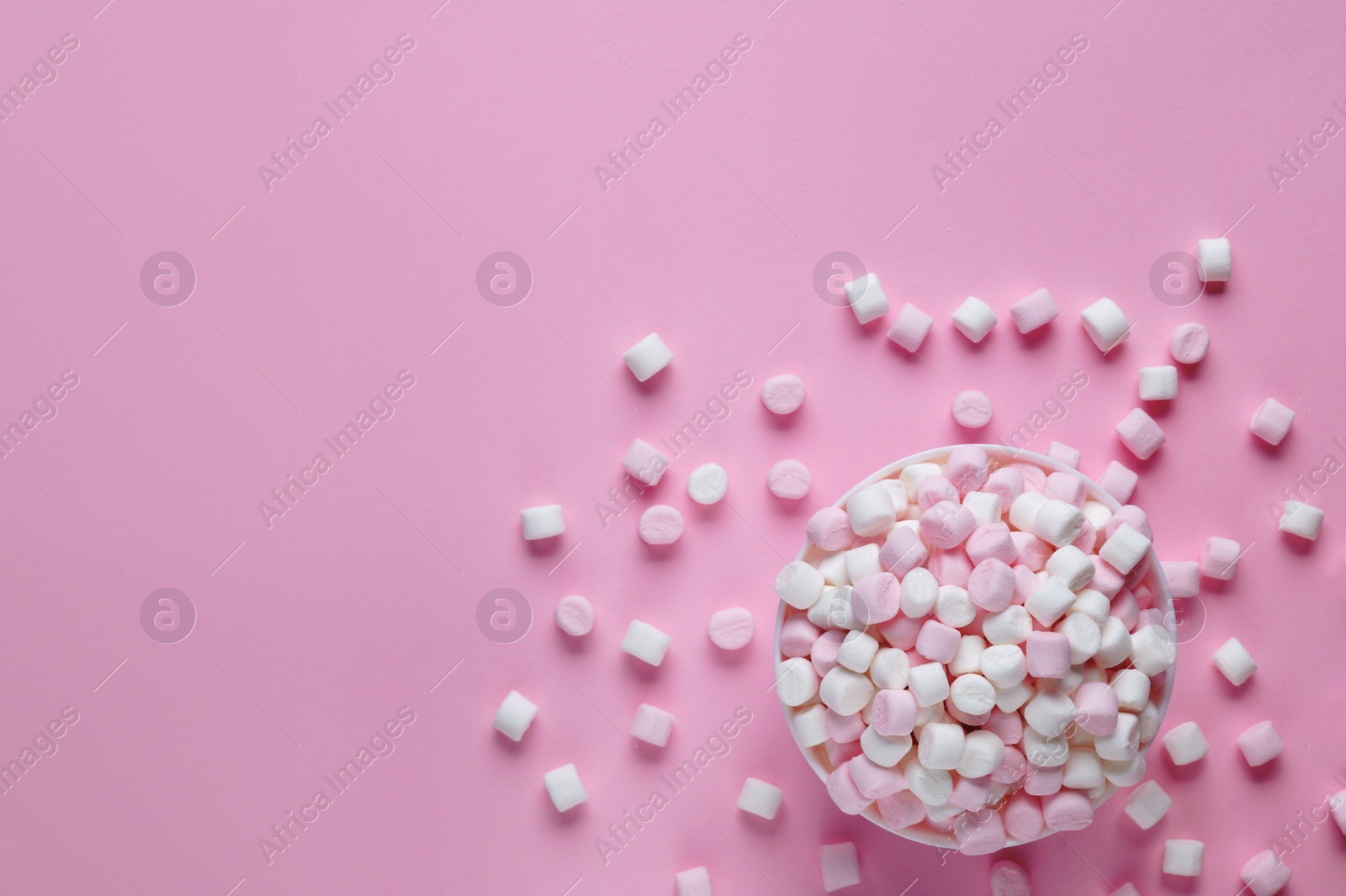 Photo of Bowl with delicious marshmallows on pink background, flat lay. Space for text