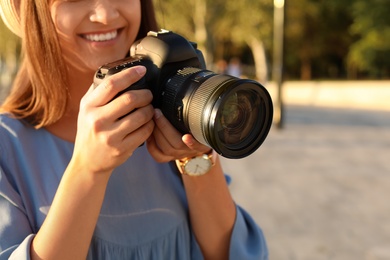 Young female photographer with professional camera on street