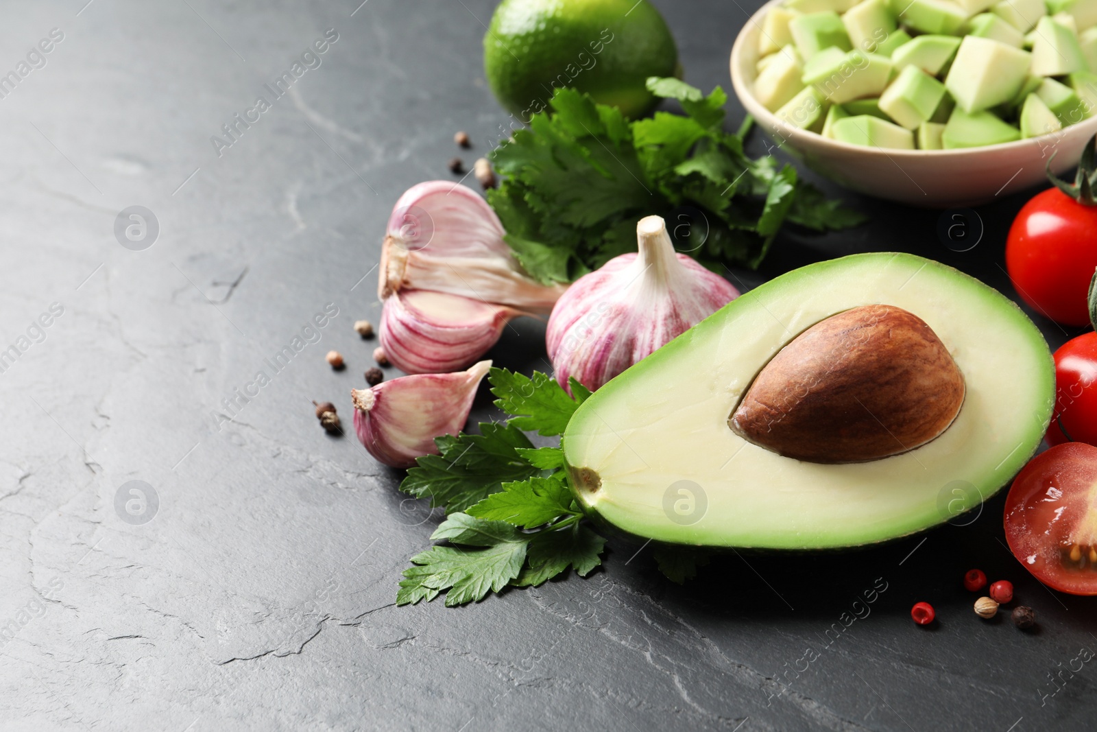 Photo of Fresh guacamole ingredients on black table. Space for text