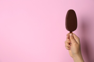 Woman holding delicious ice cream with chocolate against color background, space for text