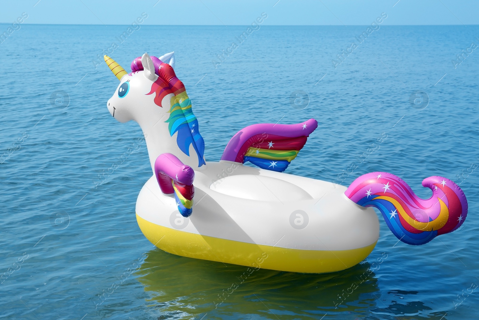 Photo of Funny inflatable unicorn ring floating on sea water. Summer vacation