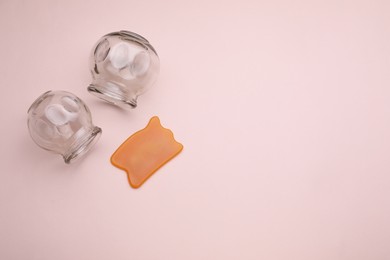 Photo of Glass cups and gua sha on pink background, flat lay with space for text. Cupping therapy
