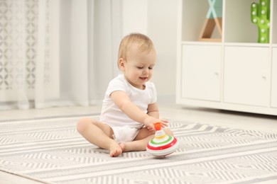 Photo of Children toys. Cute little boy playing with spinning top on rug at home