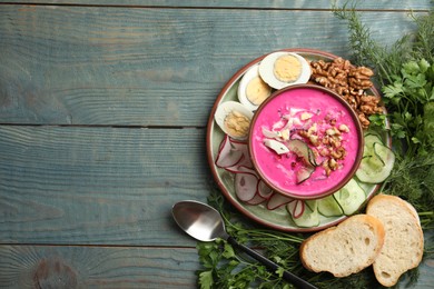 Photo of Delicious cold summer beet soup on blue wooden table, flat lay. Space for text