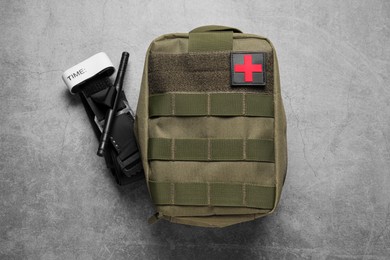 Military first aid kit and tourniquet on light grey table, flat lay