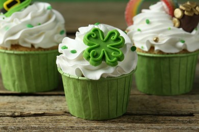 St. Patrick's day party. Tasty festively decorated cupcakes on wooden table, closeup