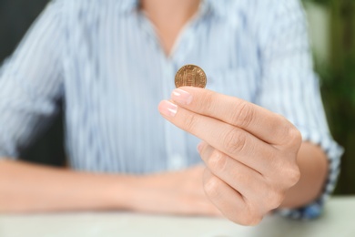 Photo of Woman holding coin at light table indoors, closeup