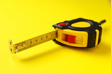 Tape measure on yellow background, closeup. Construction tool