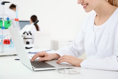 Photo of Medical student working with laptop in modern laboratory, closeup