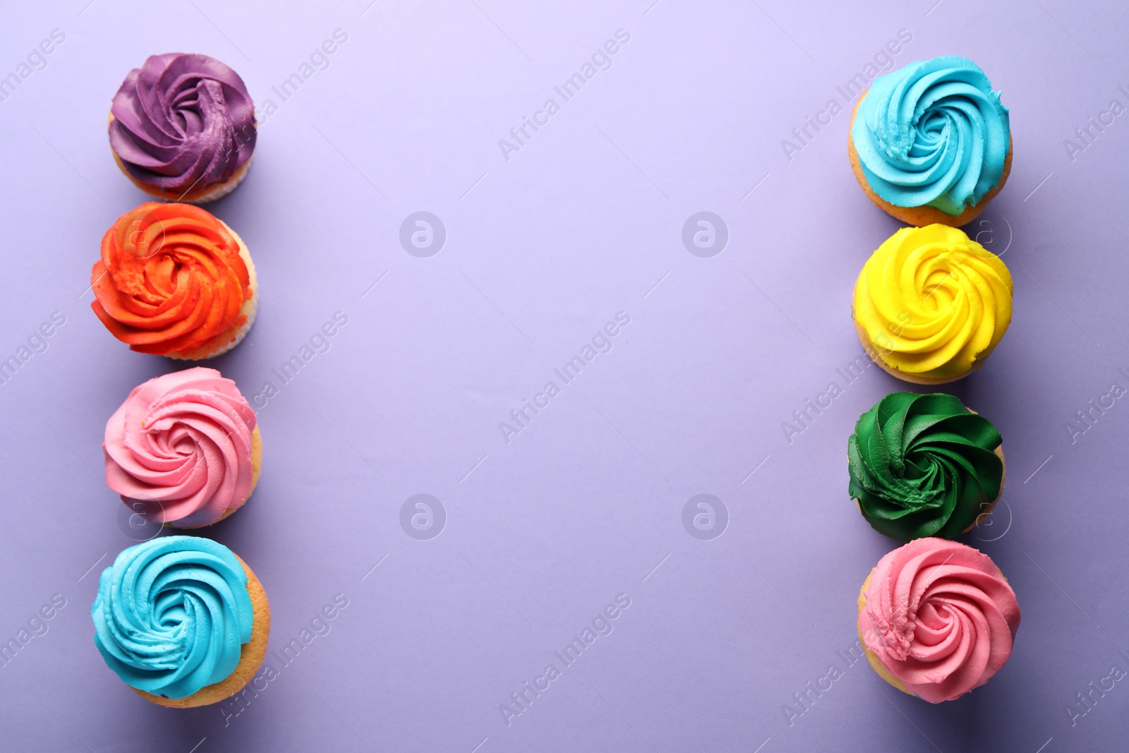 Photo of Delicious cupcakes with bright cream on violet background, flat lay. Space for text