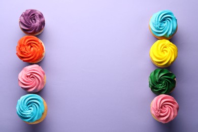 Photo of Delicious cupcakes with bright cream on violet background, flat lay. Space for text