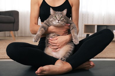 Photo of Woman hugging her cat while practicing yoga at home, closeup