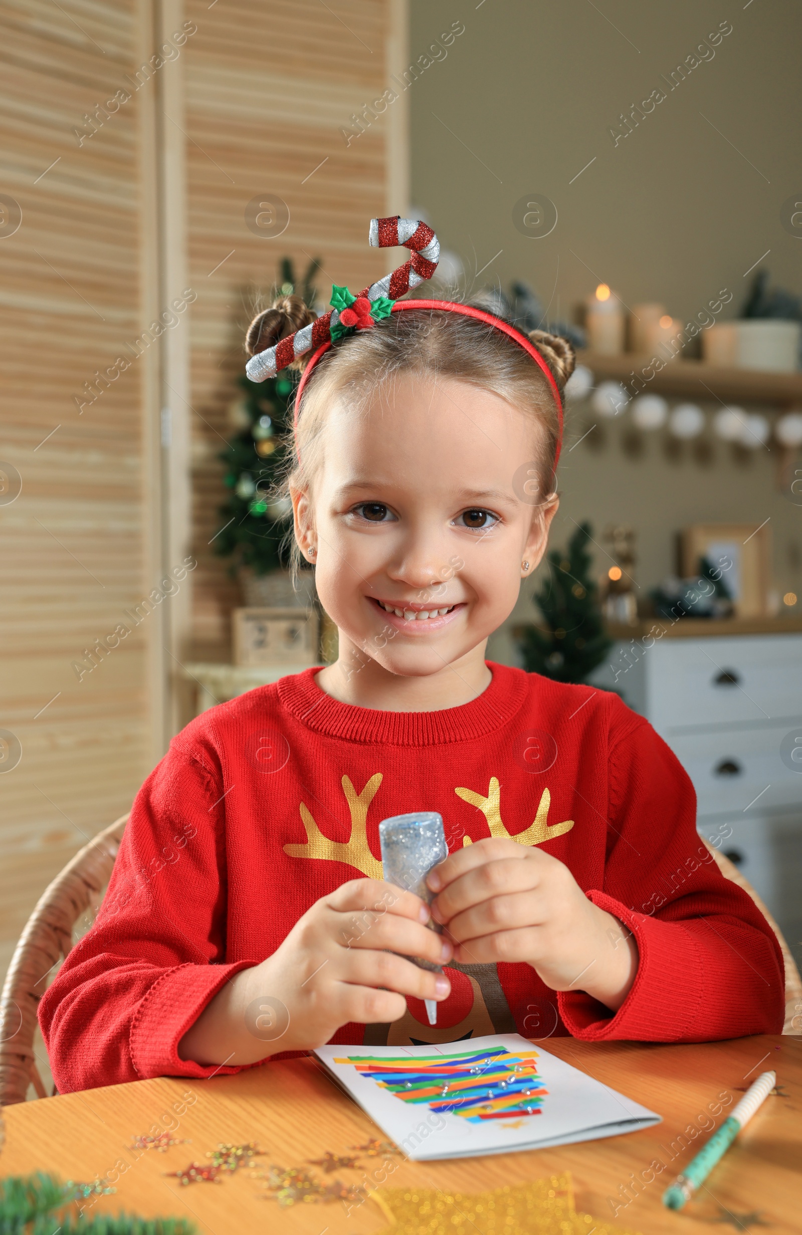 Photo of Cute little child making beautiful Christmas greeting card at home