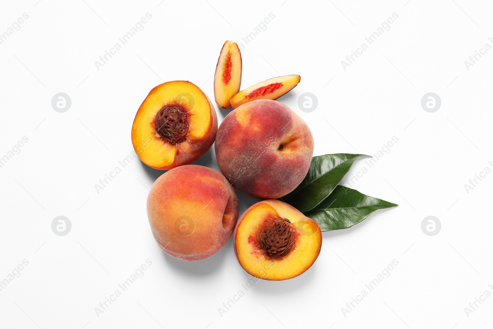 Photo of Cut and whole fresh ripe peaches with green leaves on white background, flat lay