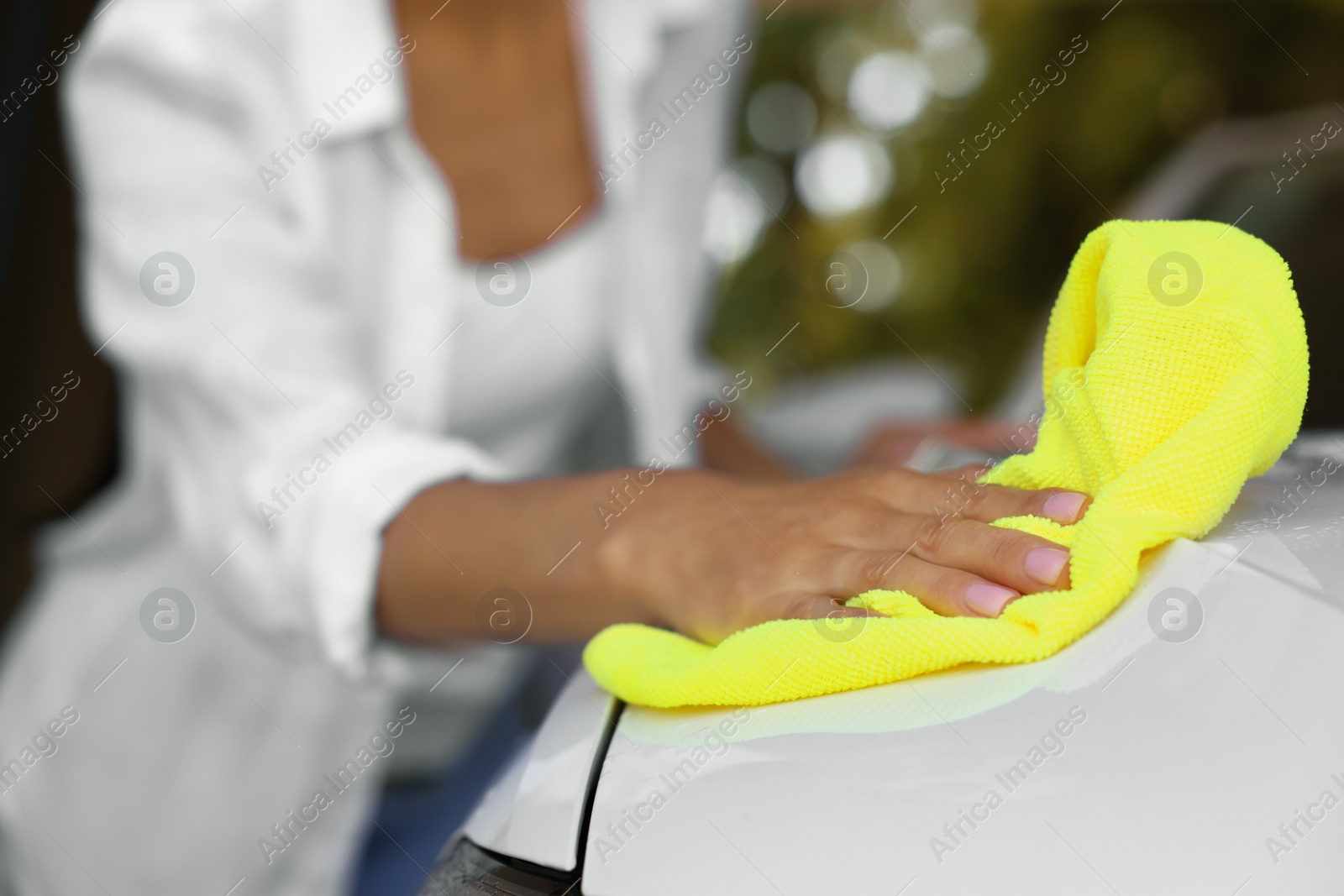 Photo of Woman cleaning car hood with rag outdoors, closeup