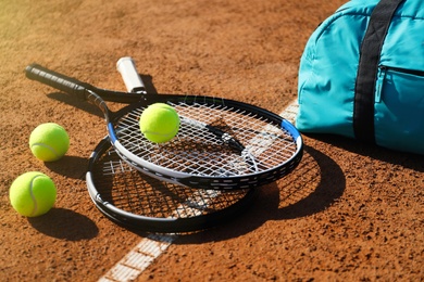 Tennis balls, rackets and bag on clay court