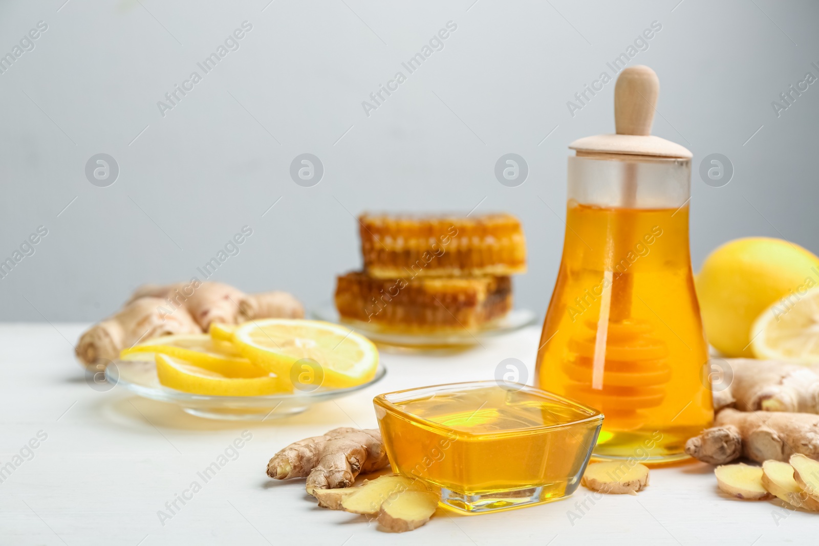 Photo of Honey, ginger and lemon on white wooden table, space for text. Natural cold remedies