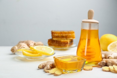 Photo of Honey, ginger and lemon on white wooden table, space for text. Natural cold remedies