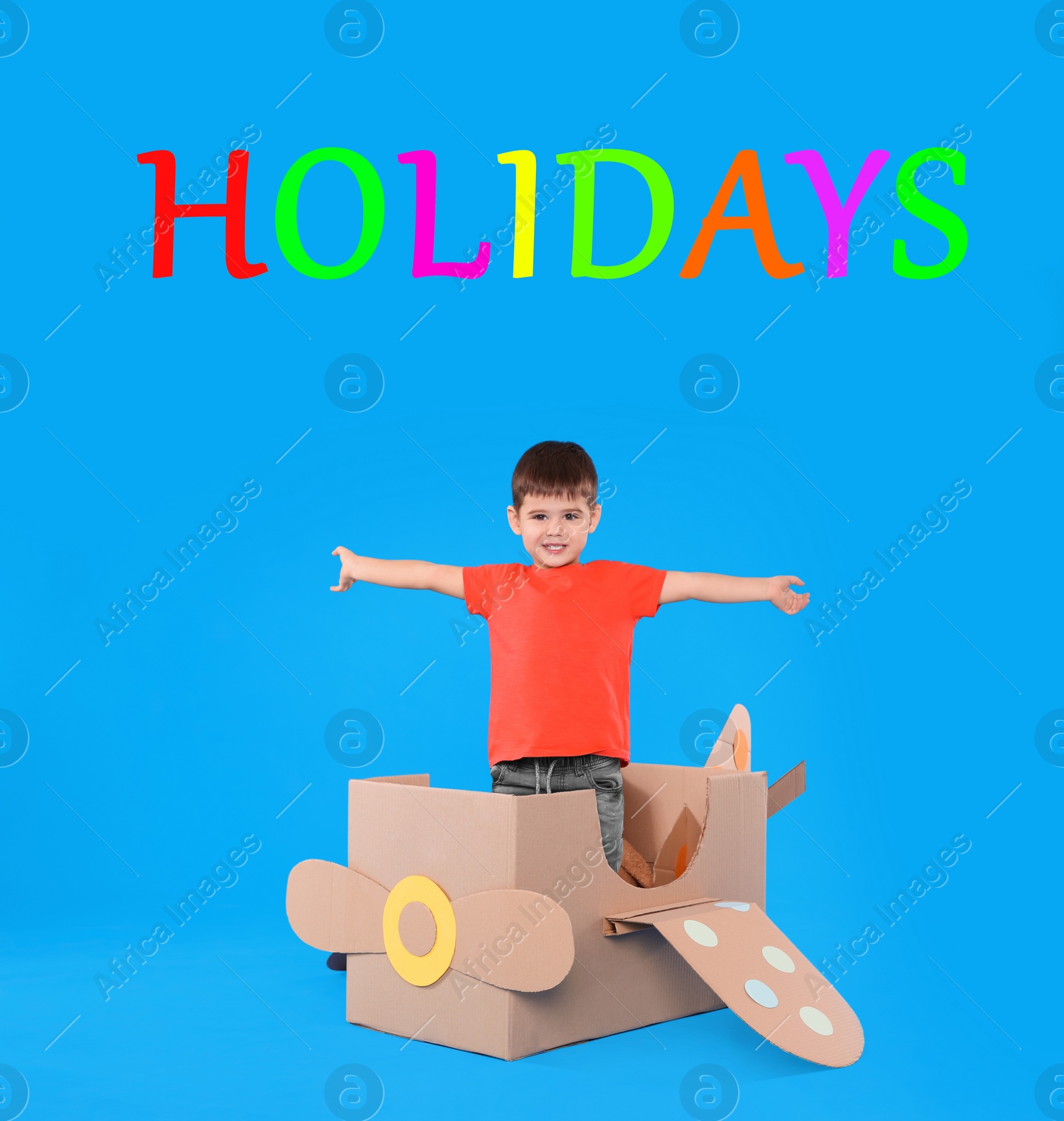 Image of School holidays. Cute little child playing with cardboard plane near blue wall