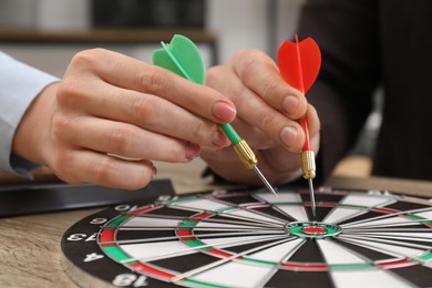 Photo of Business targeting concept. Man and woman with darts aiming at dartboard at table indoors, closeup