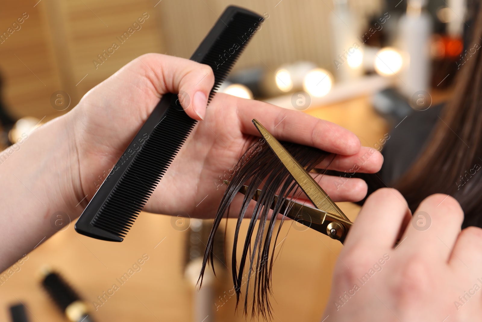 Photo of Hairdresser cutting client's hair with scissors in salon, closeup