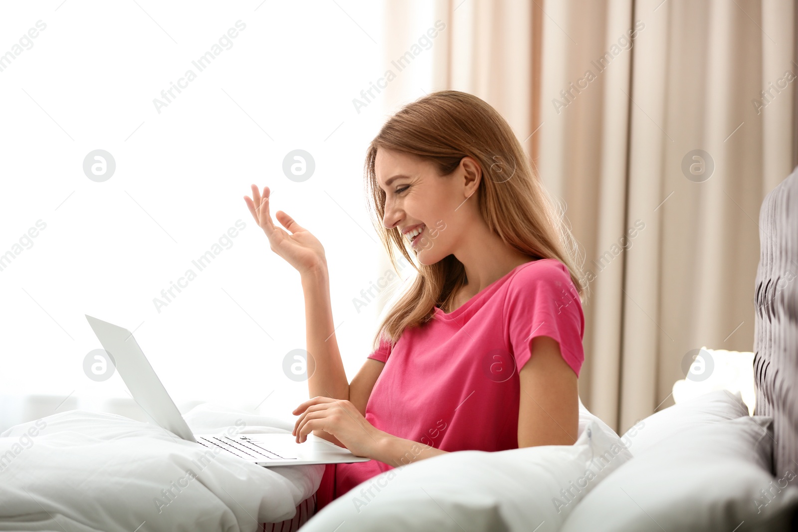 Photo of Young woman using modern laptop in bedroom